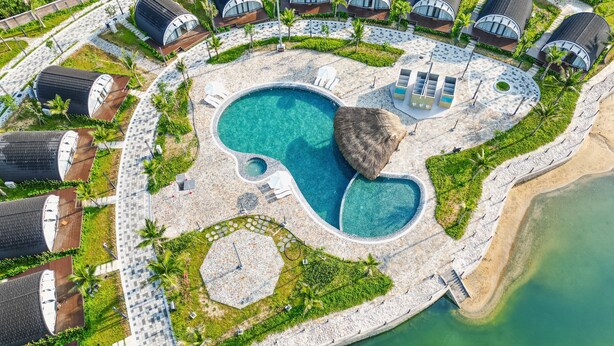 An aerial view of a resort with a central swimming pool, multiple bungalow-style accommodations, and a surrounding landscaped area. - Dau Rong Resort (Cai Chien)