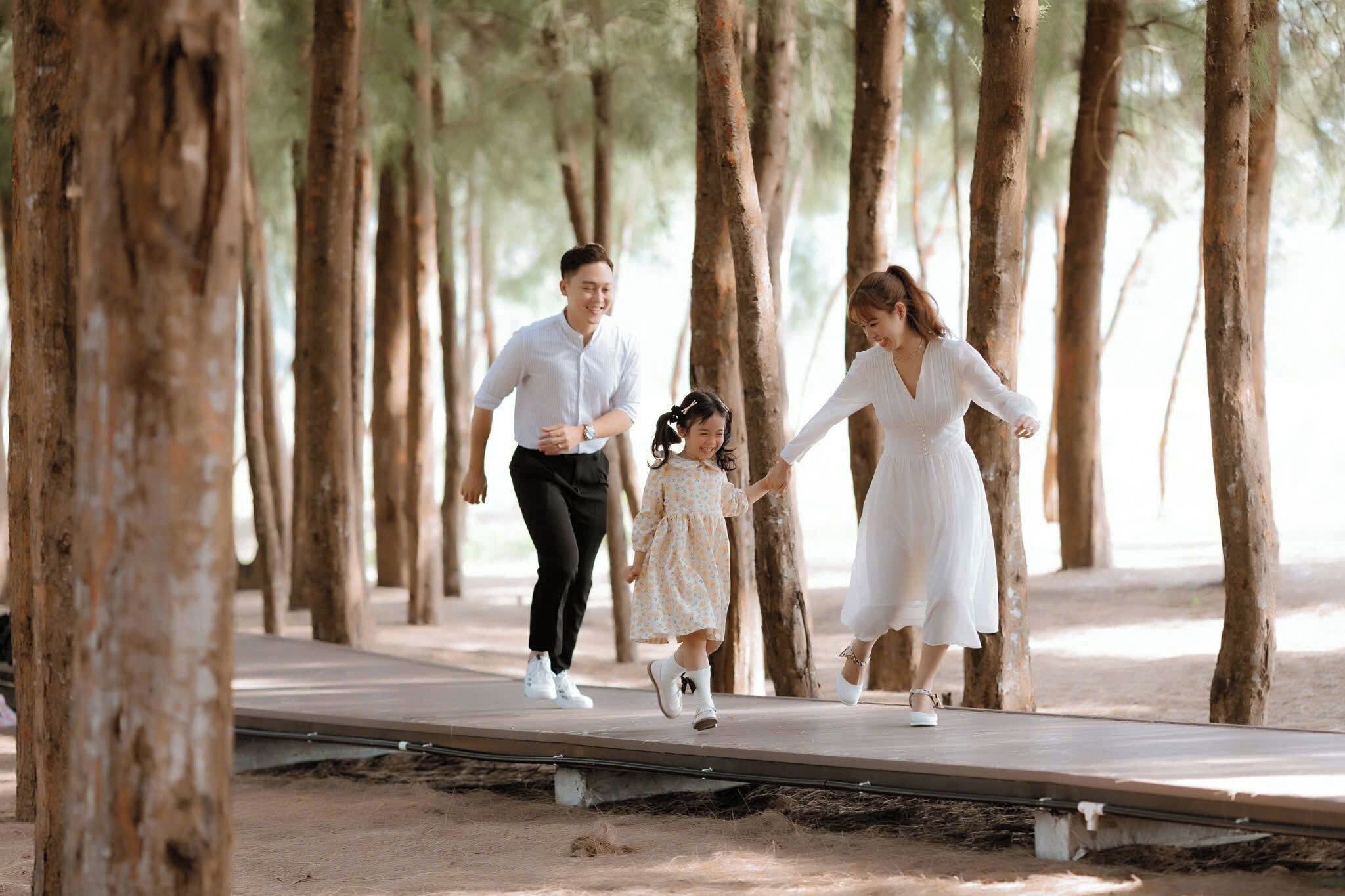 Una familia caminando sobre una pasarela de madera rodeada de árboles.