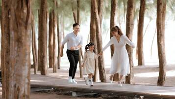 Una familia caminando sobre una pasarela de madera rodeada de árboles.