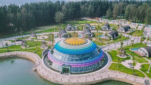 A large, multi-level, dome-shaped building with a circular water feature in the foreground. - Dau Rong Resort (Cai Chien)