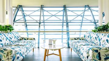 Ein modernes Zimmer mit zwei Sofas, die zu einem großen Fenster ausgerichtet sind, einem kleinen Tisch und Topfpflanzen.