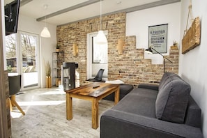 Ein modernes Wohnzimmer mit Backsteinwand, Kamin, Sofa und Holztisch.