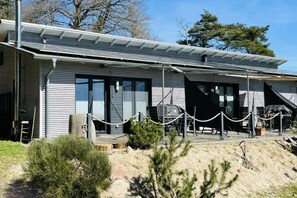 Ein modernes Gebäude mit Flachdach, großen Fenstern und einer überdachten Außenbereich mit Grill.