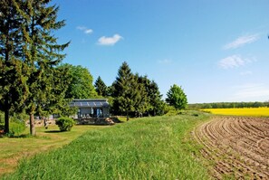Ein Haus mit Solaranlage, umgeben von Bäumen und einem Feld.