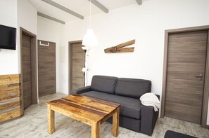 A modern living room with a wooden coffee table, grey sofa, and a hanging pendant light. - Ferienwohnungen auf dem Teschenberg Wohnung 02 - Fewo Teschenberg (Mönchgut)