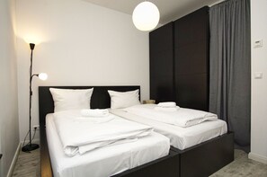 A double bed with white linens, a bedside table, a floor lamp, and a dark headboard. - Ferienwohnungen auf dem Teschenberg Wohnung 02 - Fewo Teschenberg (Mönchgut)