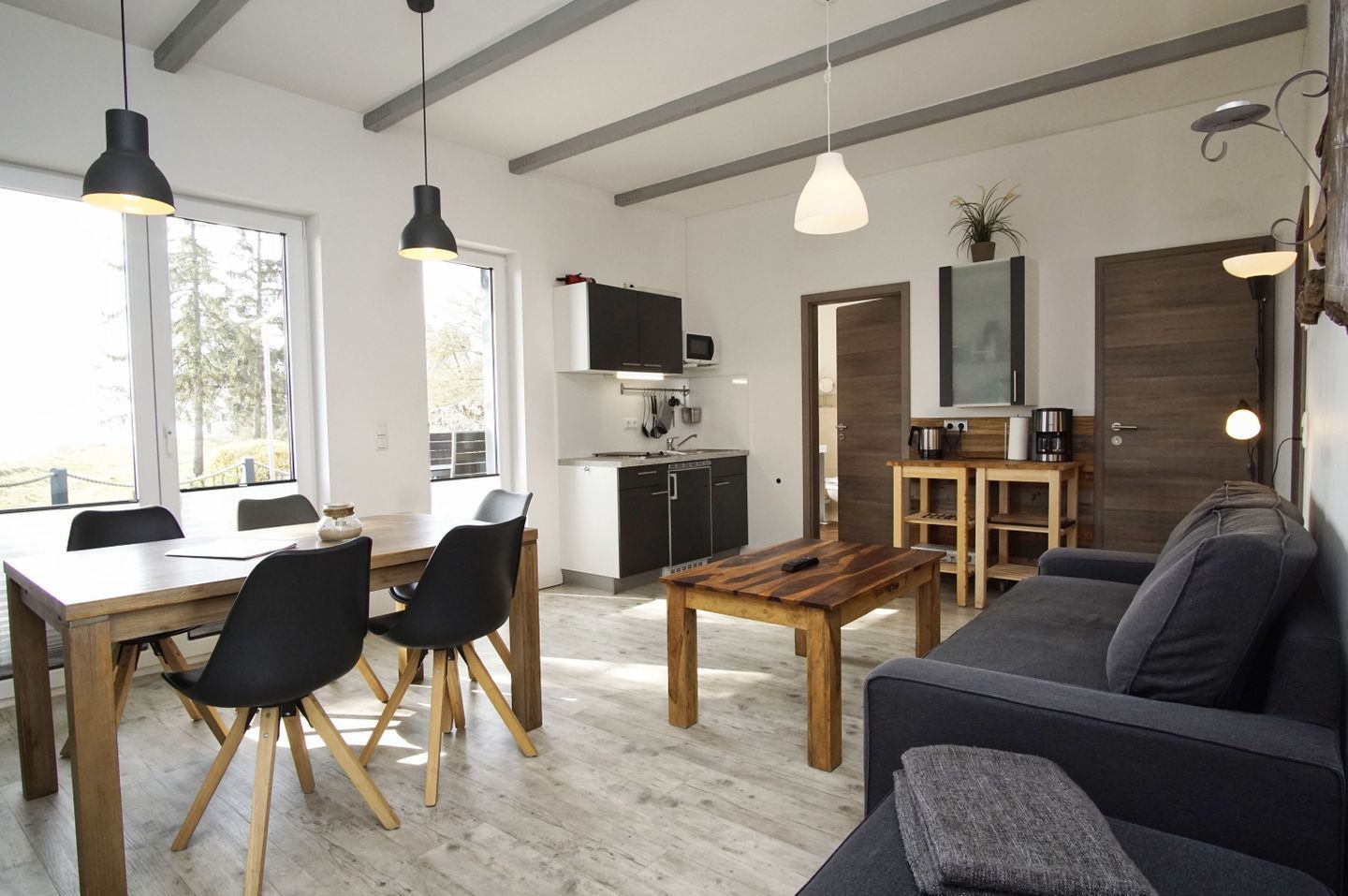 A modern living space with a dining area, kitchen, and seating area.