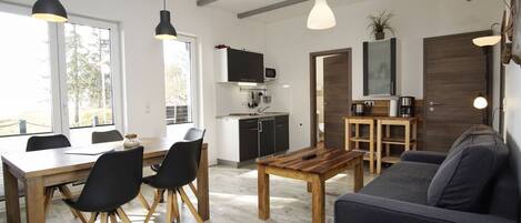 A modern living space with a dining area, kitchen, and seating area.