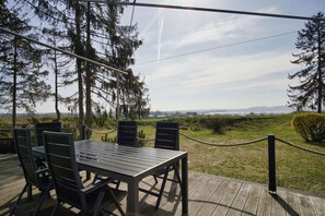 Un espace extérieur aménagé avec une table et des chaises, délimité par une barrière en corde et entouré d’arbres.