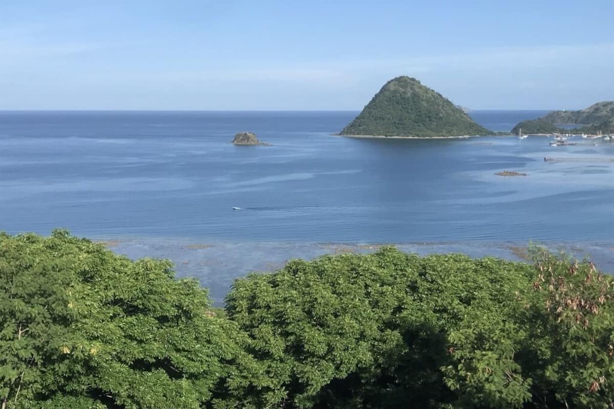 A coastal landscape with a prominent hill and calm sea.