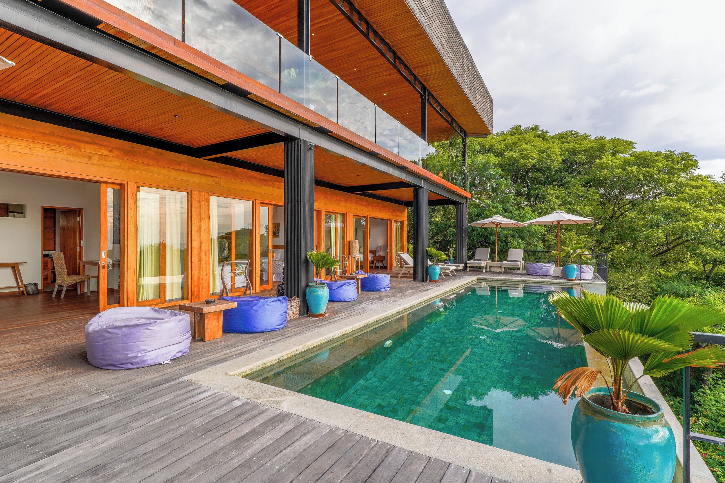 A modern house with a swimming pool, wooden deck, and outdoor seating.