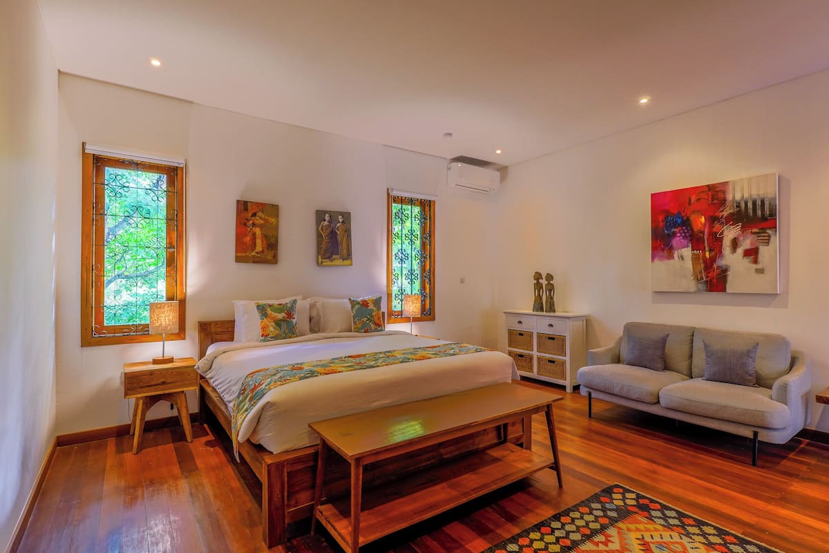 A bedroom with a bed, a bench, a sofa, and a small cabinet.
