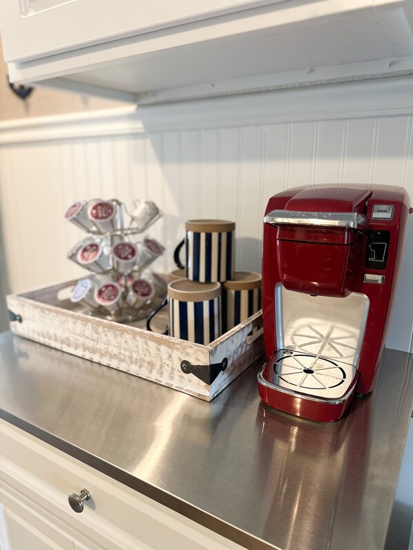 A kitchen counter with a red coffee maker, a tray with striped mugs, and a coffee machine with a display. - NEW LISTING *Lakefront* Sleeps 6* Pool* (Lake Ozark)