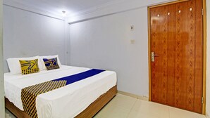 Ein Schlafzimmer mit Holztür, einem Bett mit weißer Bettwäsche und gemusterten Kissen.