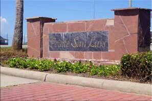 A stone sign with "Pointe San Luis" engraved in gold lettering.