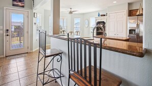 A modern kitchen with a central island, stainless steel appliances, and a dining area with bar stools.