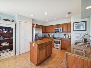 A kitchen with wooden cabinets, a stainless steel refrigerator, a microwave, and a sink.