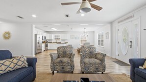 Un salon spacieux avec des fauteuils à motifs, un canapé et un ventilateur de plafond.
