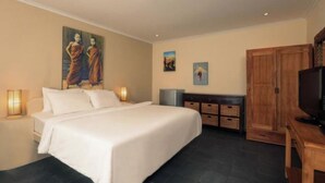 Een hotelkamer met een groot bed, een houten garderobe, een televisie en kunstwerken aan de muur.