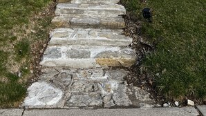 A two-story house with a stone facade, a green door, and a stone pathway leading to the entrance. - Stanley Cozyside (Middletown)