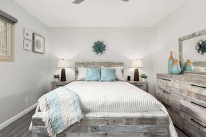 A bedroom with a bed, two bedside tables, a dresser, and a ceiling fan.