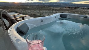 A hot tub with a glass of pink drink, surrounded by a wooden deck and overlooking a mountainous landscape. - Northwest View Quincy easy walk to Gorge Amphitheater, Cave B Winery, Sagecliffe (Quincy)