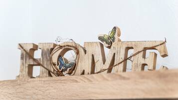 Holzbuchstaben, die das Wort 'HOME' bilden, mit einem Schmetterling auf einem der Buchstaben.