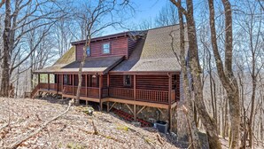 A wooden cabin with a porch and a stone foundation, surrounded by trees. - Rustic mountain cabin with amazing view, pool table, jetted tub, W/D & fireplace (Boone)