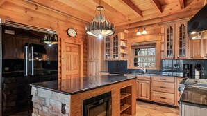 A wooden cabin-style kitchen with a stone island, stainless steel appliances, and a chandelier. - Rustic mountain cabin with amazing view, pool table, jetted tub, W/D & fireplace (Boone)