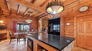 A wooden cabin interior with a kitchen island, dining area, and a large wooden door. - Rustic mountain cabin with amazing view, pool table, jetted tub, W/D & fireplace (Boone)