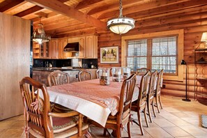 A wooden cabin interior with a dining table set for six, surrounded by wooden chairs.