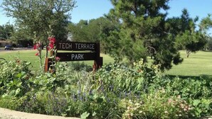 A sign for Tech Terrace Park surrounded by lush greenery and trees.