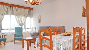 Um quarto aconchegante com uma mesa de jantar de madeira, cadeiras, um sofá e um candelabro.