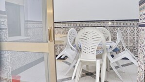Uma área de refeições com mesa e cadeiras, um revestimento de azulejos na parede e uma porta que dá para outro cômodo.