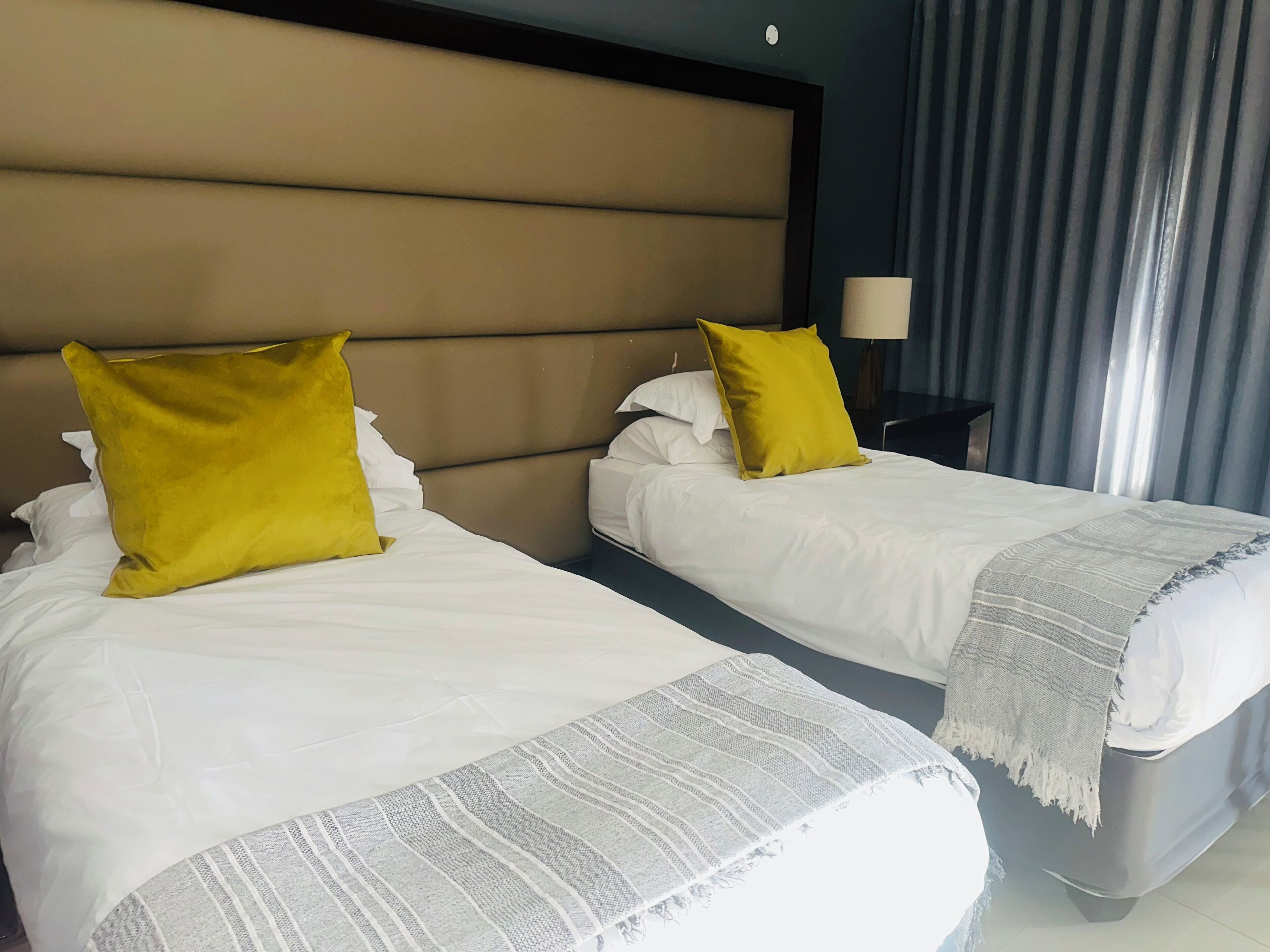 Ein Hotelzimmer mit zwei Betten, jeweils mit weißer Bettwäsche und einem gelben Kopfkissen.