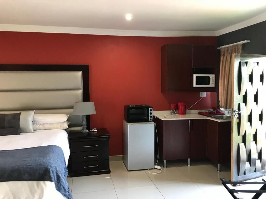 A compact hotel room with a bed, a small kitchenette, and a microwave.