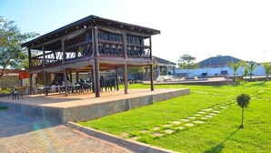 A two-story building with a covered outdoor seating area and a paved walkway. - 1 Oak lodge (Thulamela)