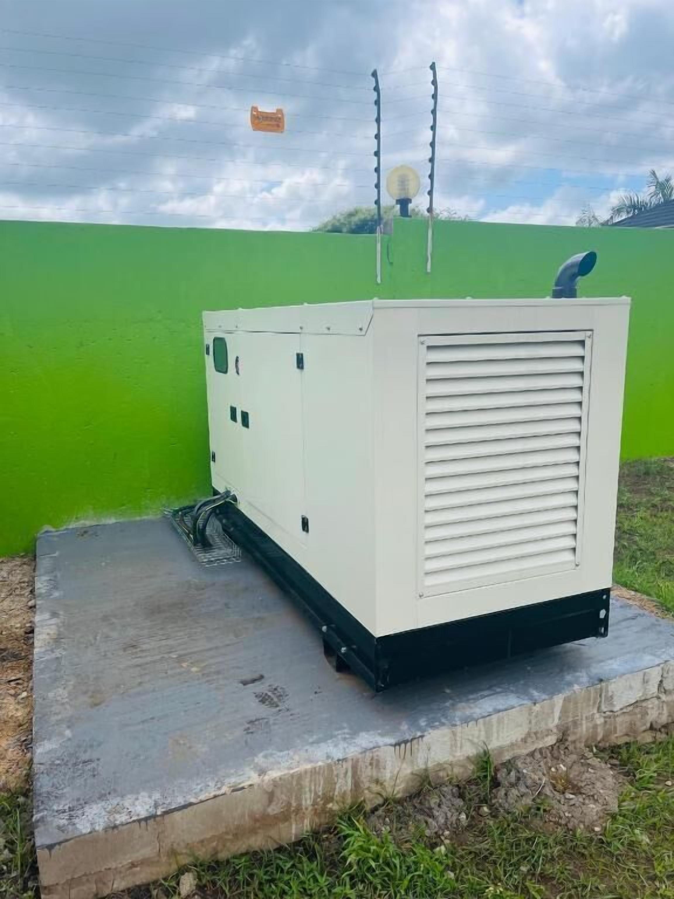 A portable generator with a white body and black base, placed on a concrete platform outdoors.