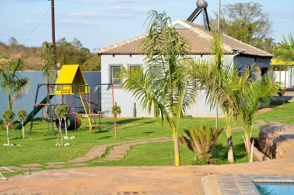 Un barrio residencial con una casa, un parque infantil pequeño y una piscina.