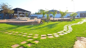A well-maintained outdoor area with a covered seating area, a paved walkway, and a grassy lawn. - 1 Oak lodge (Thulamela)
