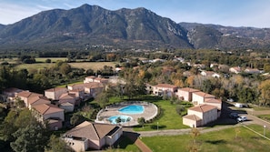 A residential area with houses, a swimming pool, and mountains in the background.