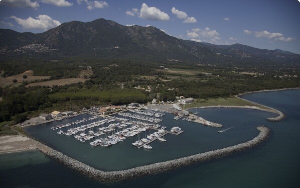 An aerial view of a marina surrounded by mountains, with boats docked and a small building nearby.