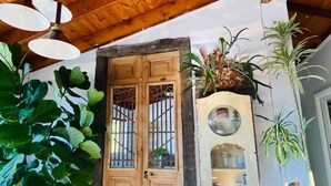 Une porte en bois avec un portail en métal, des plantes en pot et un luminaire suspendu.