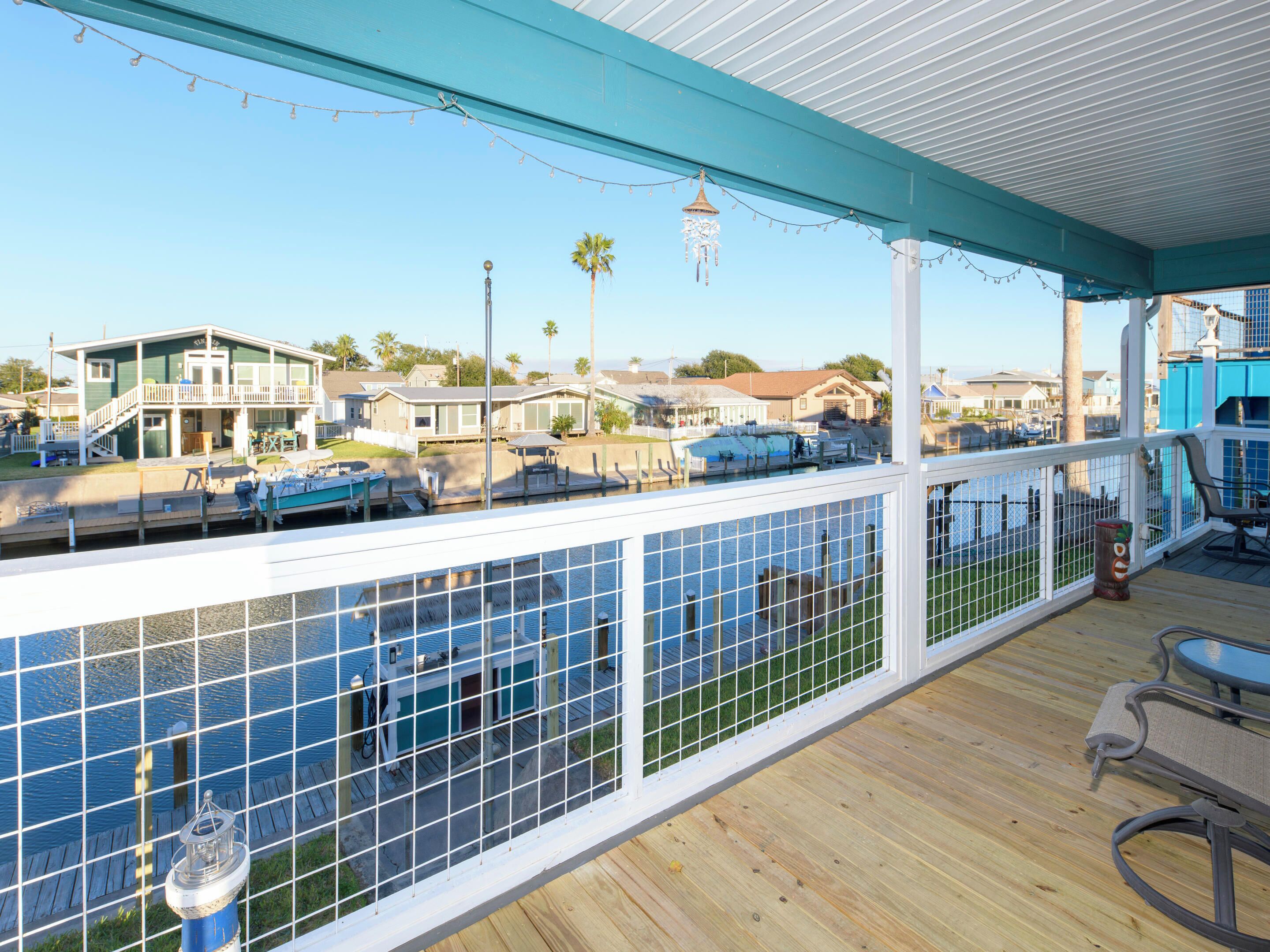 Une terrasse couverte offrant une vue sur un port de plaisance, avec des bateaux et des maisons en arrière-plan.