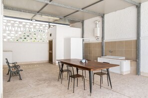 Uma cozinha com mesa e cadeiras de madeira, geladeira branca e painel de azulejos.