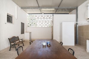 Un salón de conferencias con una larga mesa, sillas, un banco y un panel decorativo.