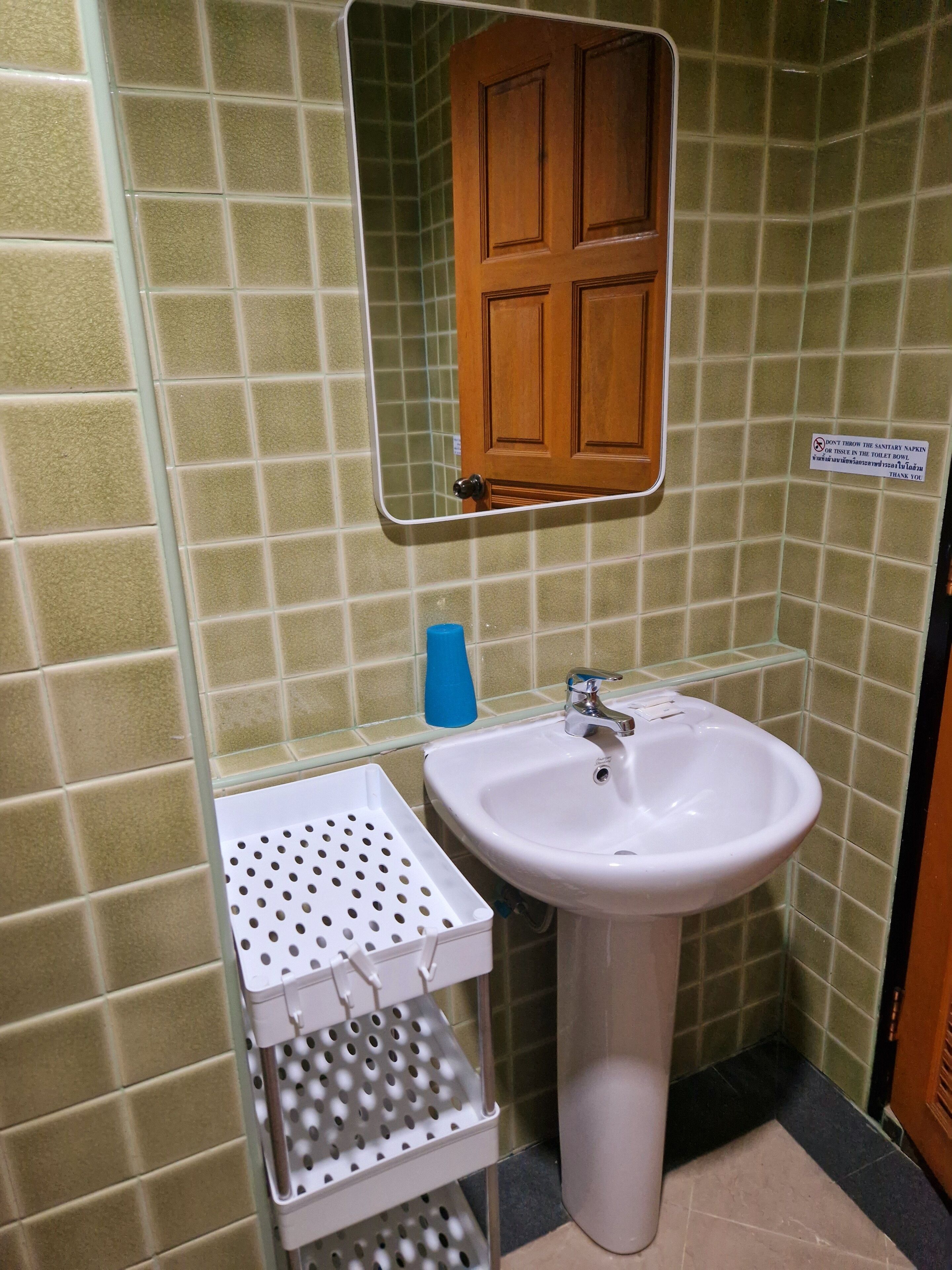 A bathroom with a white sink, a mirror, and a wooden door.