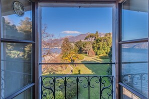 Un balcón con vista a un lago, árboles y montañas.