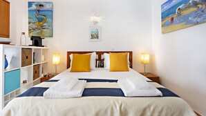 A hotel room with a large bed, two bedside tables with lamps, a wooden headboard, and artwork on the walls.