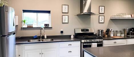 A modern kitchen with white cabinets, stainless steel appliances, and a window with a view.